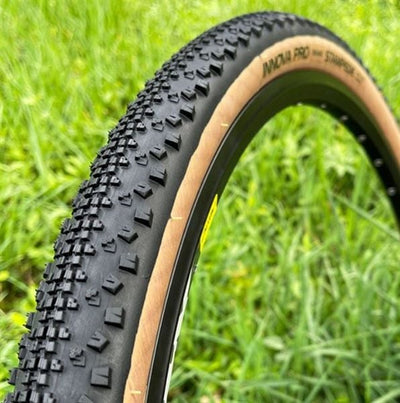 Close-up of a Innova Pro Stampede bicycle tire with tread pattern on grass background